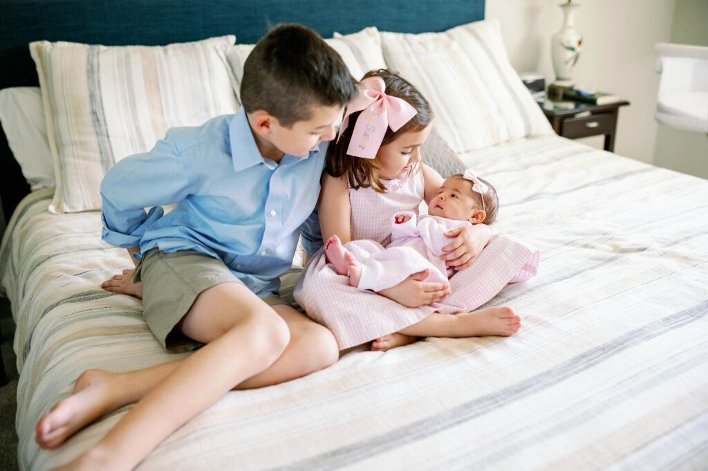 brother and sister holding their newborn sister