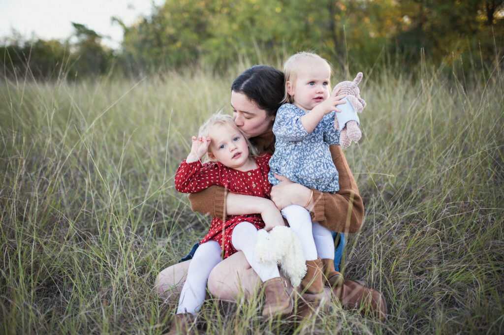 Mom holding two young daughters for family picture
