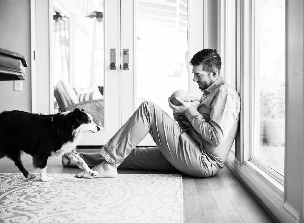 dad and family dog look at newborn