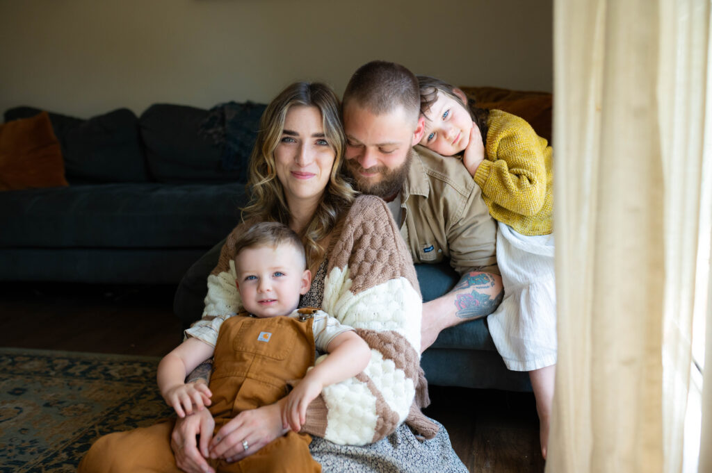Mom holding young son and dad with sister watching