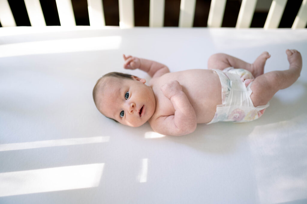 newborn baby looking around in crib