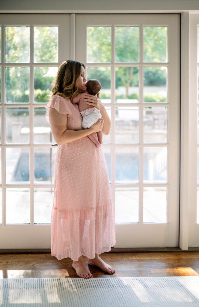mom holding newborn daughter near window
