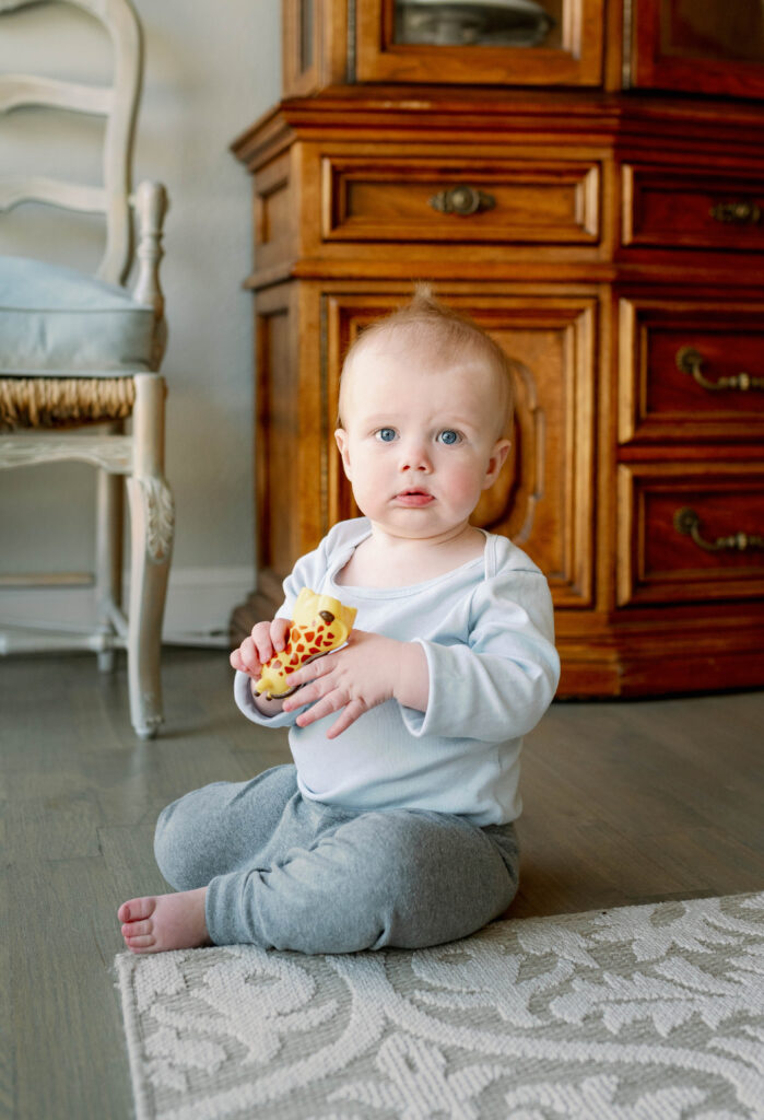baby holding toy for milestone photo