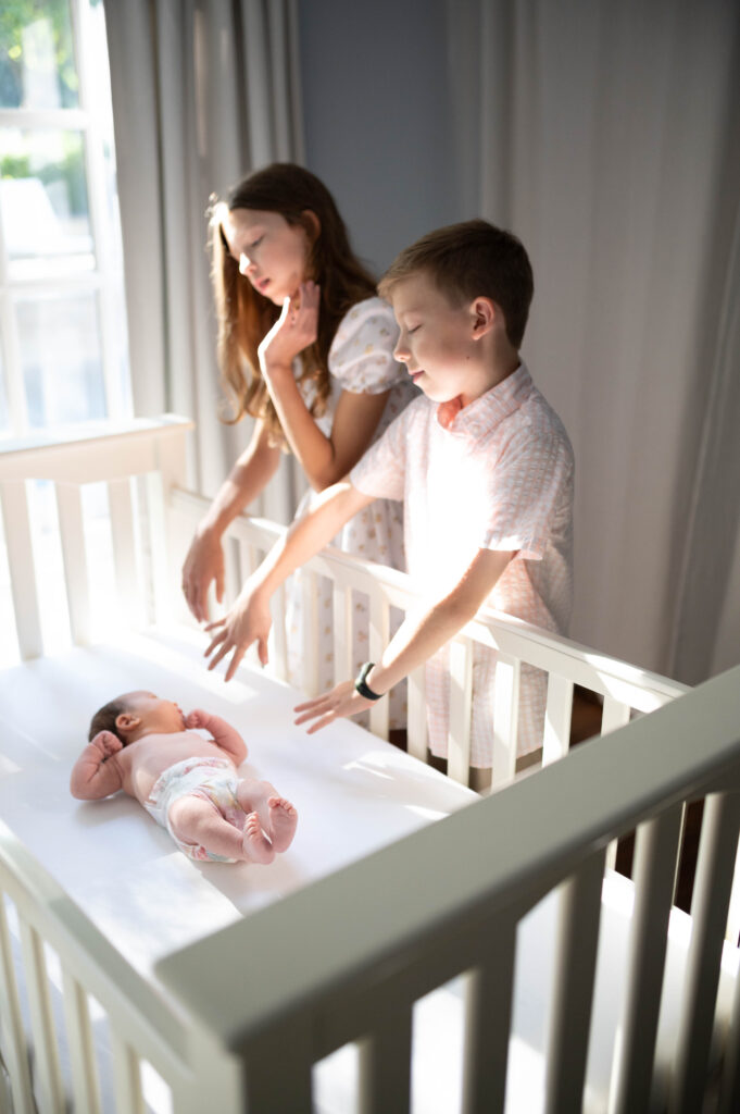 older siblings looking at newborn during in home newborn session in fort worth