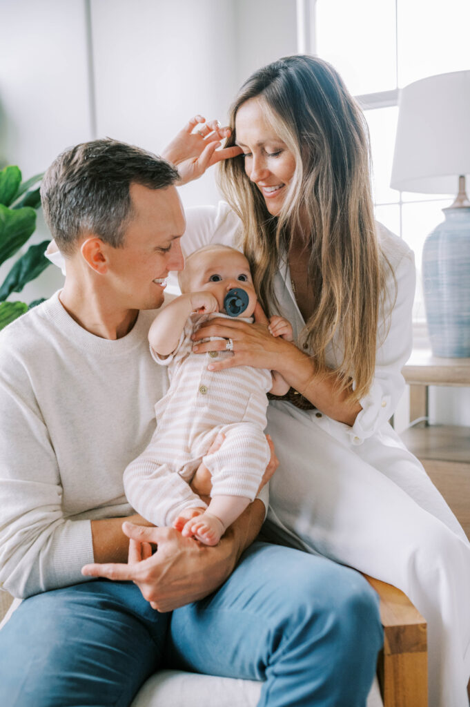 mom and dad in neutral outfits holding newborn baby

