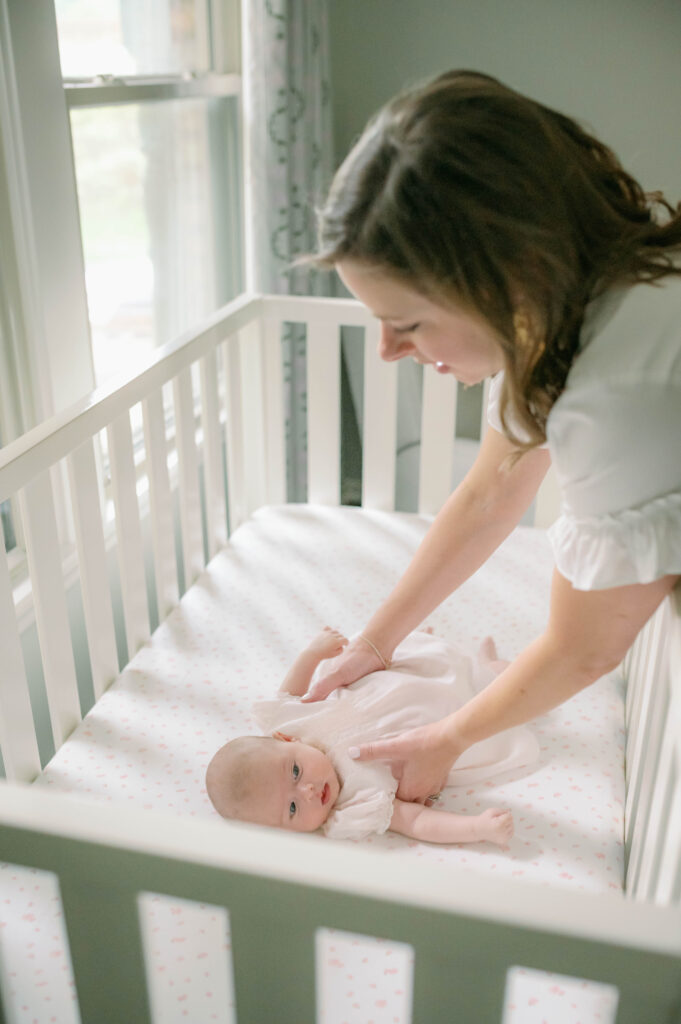 Aledo newborn photographer, Allison Krogness, captures a mom reaching into her baby girl's crib to lift her up.