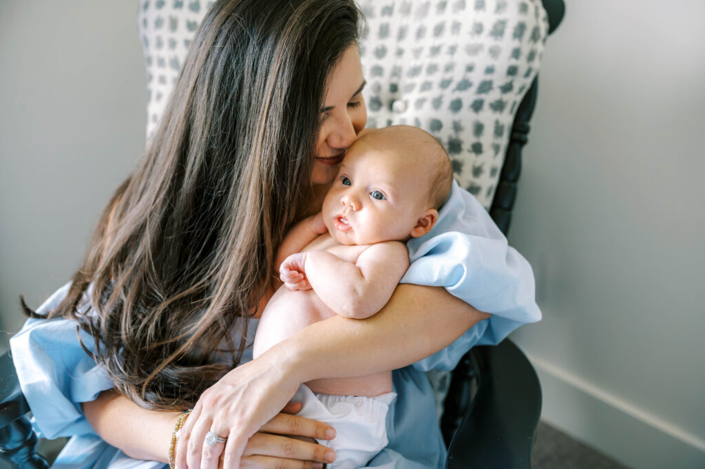 Mom whispers into the newborn baby's ear during an Aledo in-home newborn session.