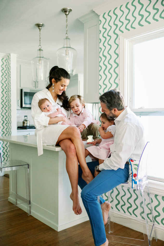 A Fort Worth family in their kitchen, talking with each other during a newborn photo session.
