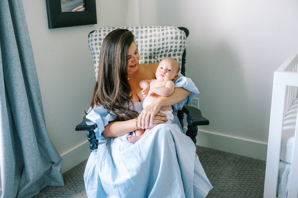 Mom, wearing a long blue dress, cuddles with the baby during a photo session with Allison Krogness.