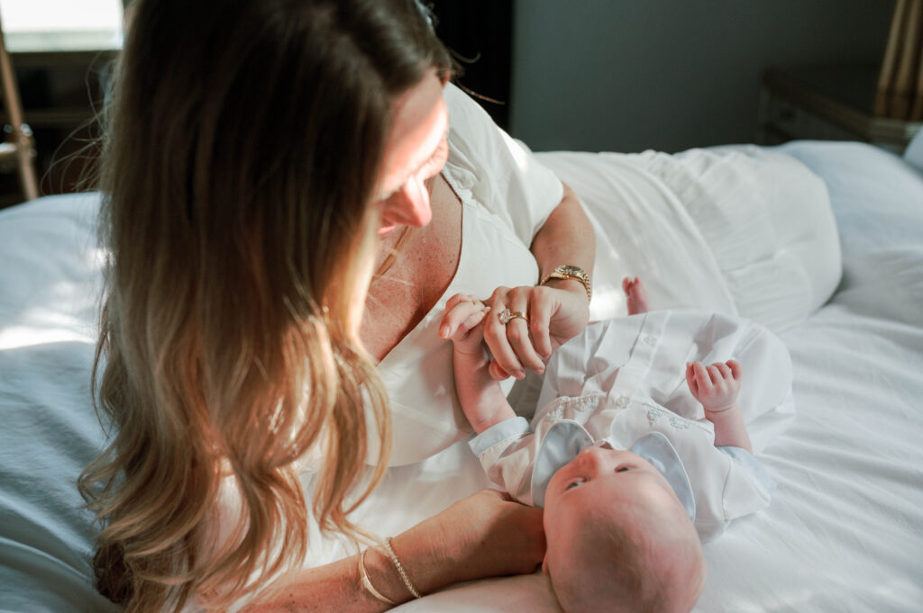 Aledo newborn photographer, Allison Krogness, captures mom on her bed playing with the newborn's hands.

