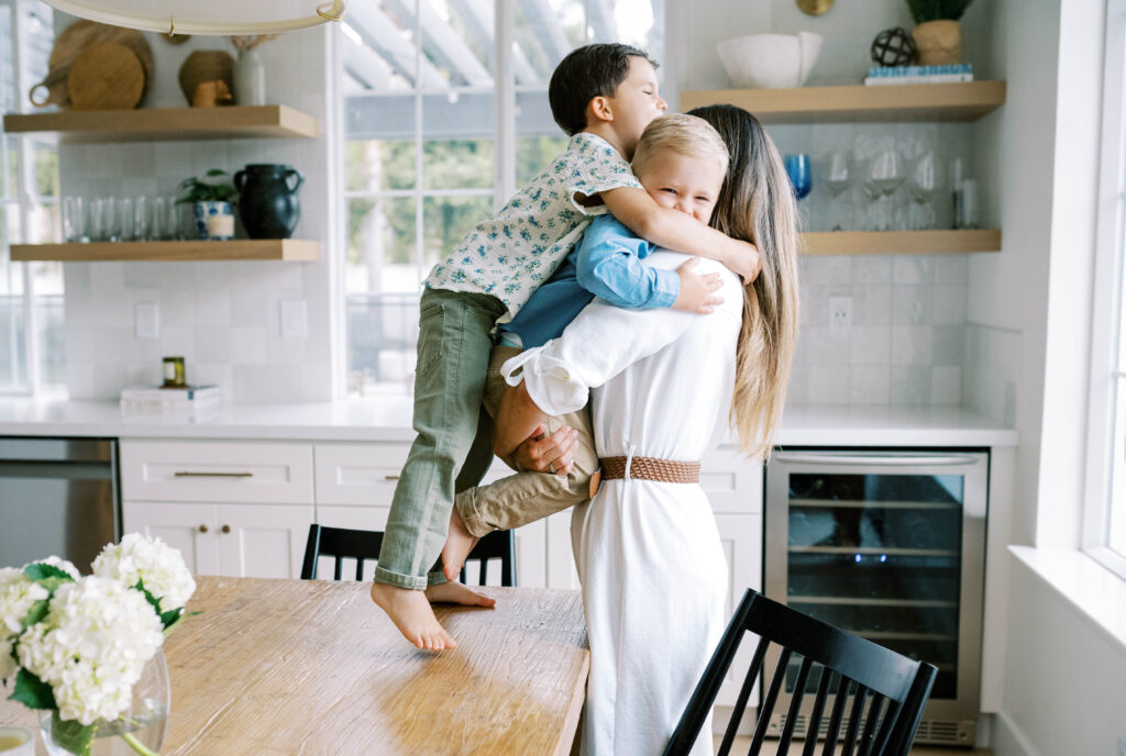 Mom is hugging both of her children during an in-home newborn session.
