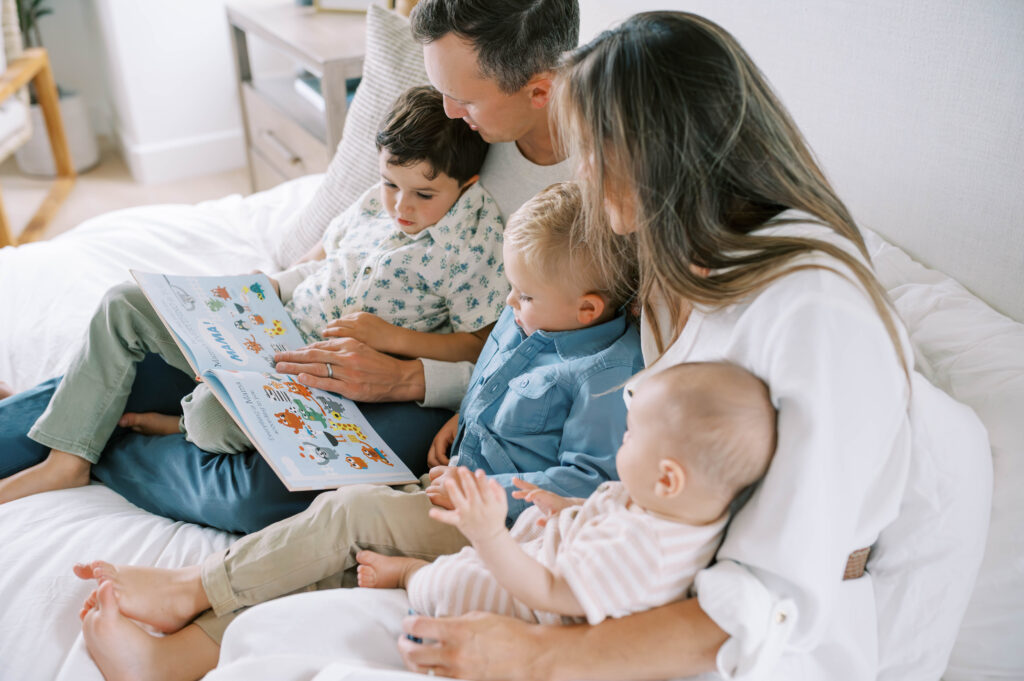Fort Worth newborn photographer cpatures a family reading a book together during an in-home session.
