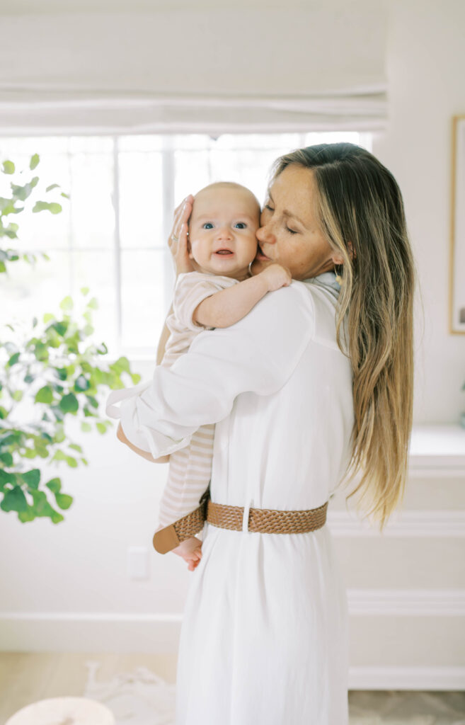 A mom kisses her newborn sons cheek during a Fort Worth baby session with Allison Krogness.
