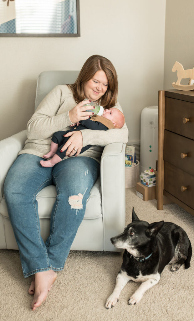 Allison Krogness includes pets in newborn sessions, and the dog looks up as the mom holds the newborn.