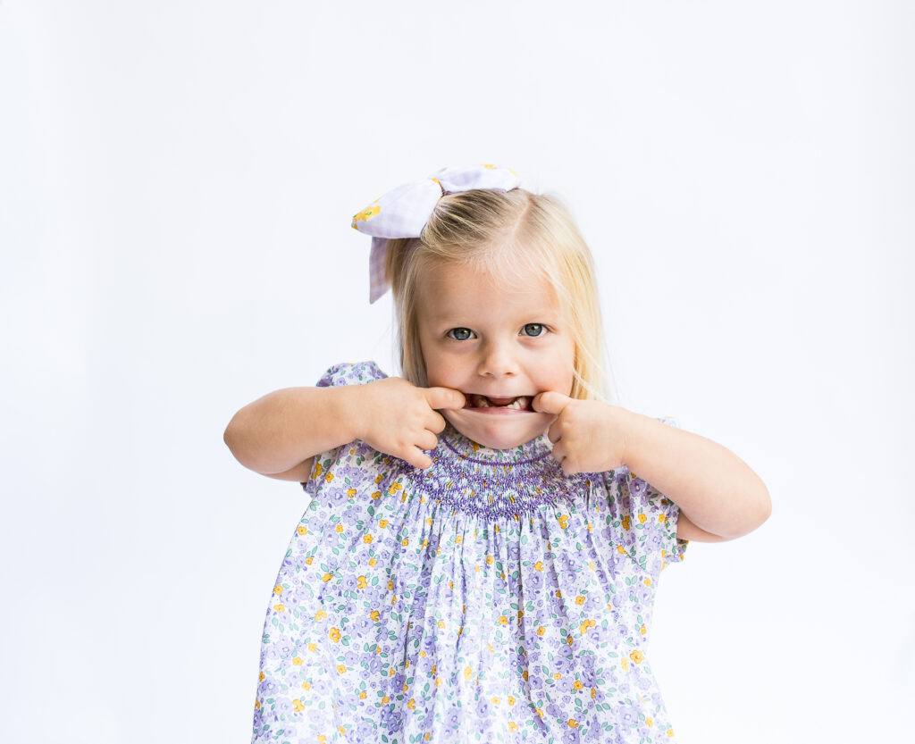 A young girl makes a silly face for the camera during a Fort Worth preschool personality session.
