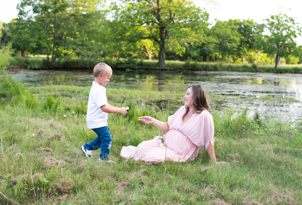 A mother receives a bouquet of wildflowers from her son during an outdoor DFW maternity session.

