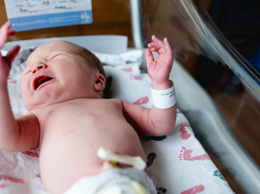 Fort Worth fresh 48 photographer Allison Krogness captures a newborn's hand while the newborn cries in the bassinet.
