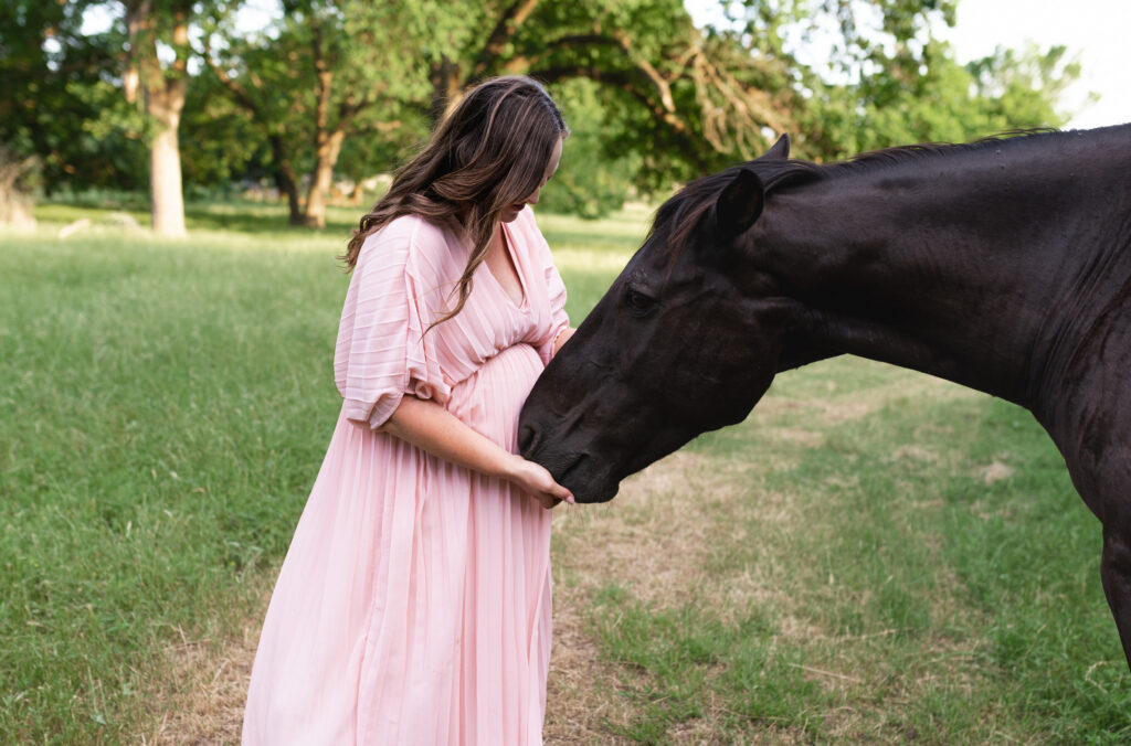 A pregnant mom nuzzles the head of her horse during an outdoor DFW maternity session during golden hour.
