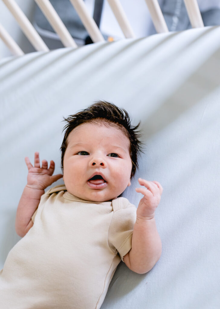 A close-up image of a newborn in his crib highlighting his thick hair.

