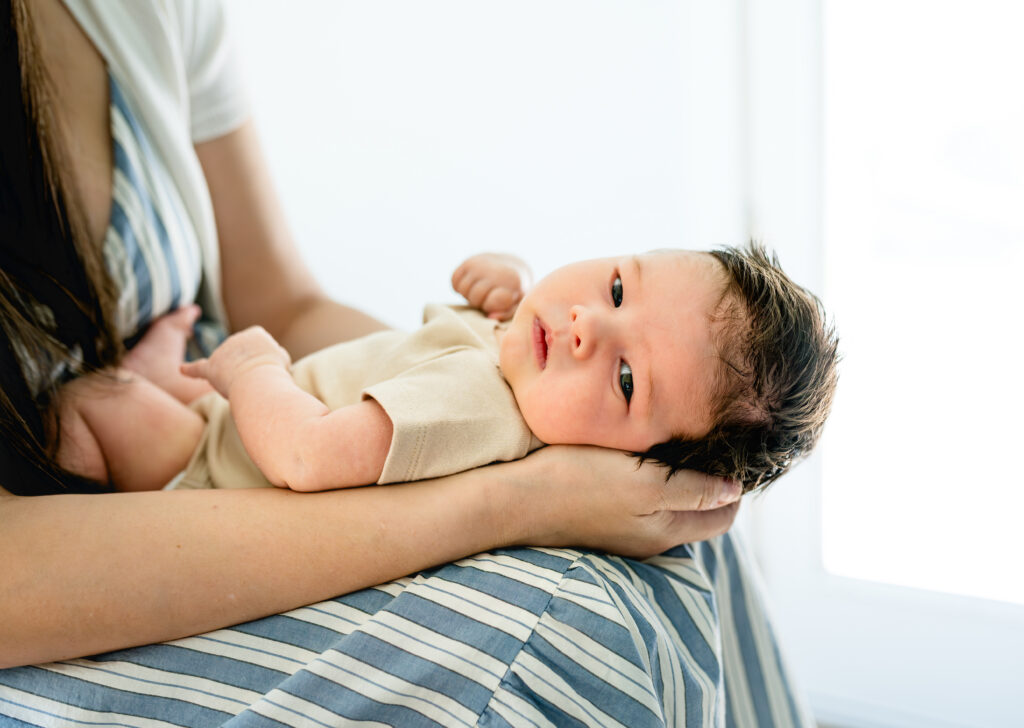 During a Fort Worth newborn session, a mom holds her newborn on her lap.
