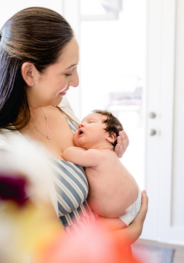 Peering through flowers, a mom cradles her newborn son.
