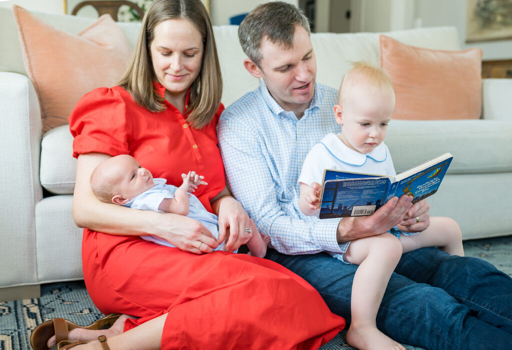 Whole family portrait with newborn baby, relaxed and unposed family photography enjoying a story together.
