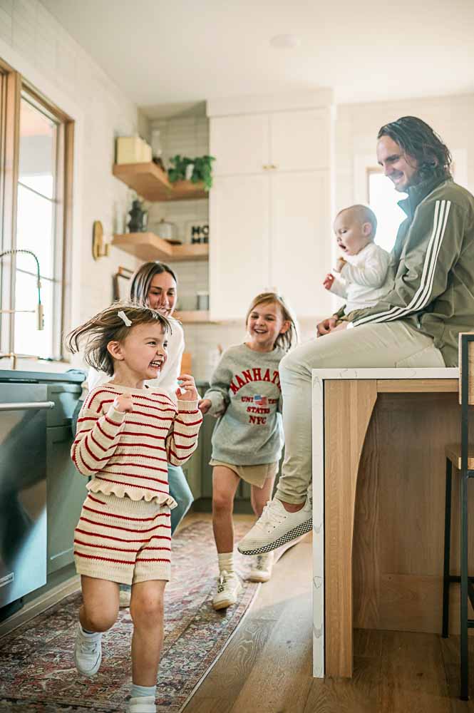Fort Worth family lifestyle photographer Allison Krogness captures siblings playing around the kitchen island during a photo session.
