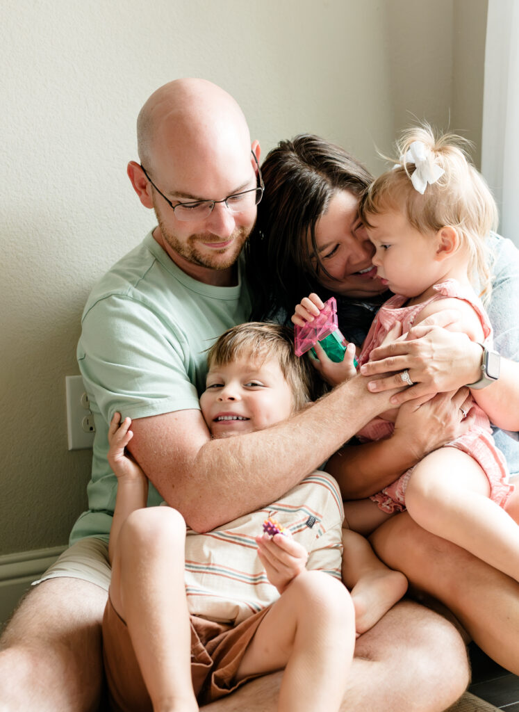 During a candid family photo session, dad wraps his arms around his whole family in a fun embrace.
