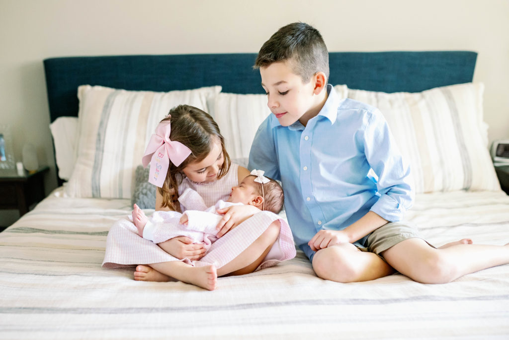 Older siblings holding newborn for in home newborn photography session
