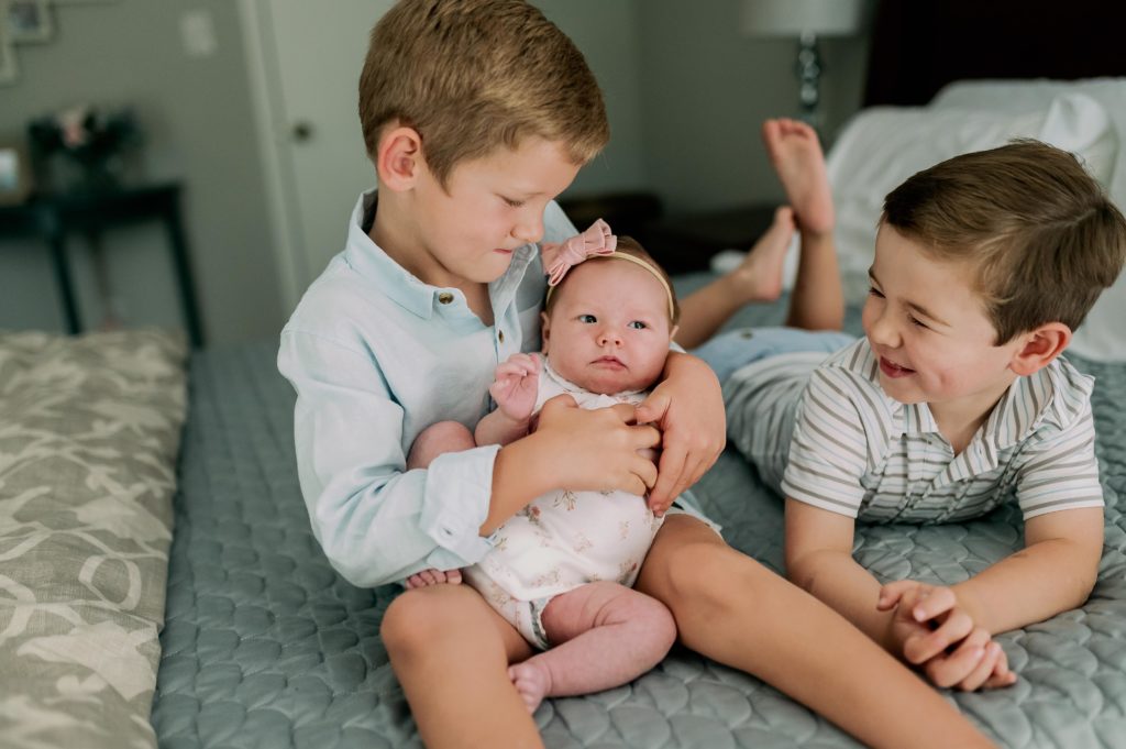 older siblings holding newborn during in home photography session
