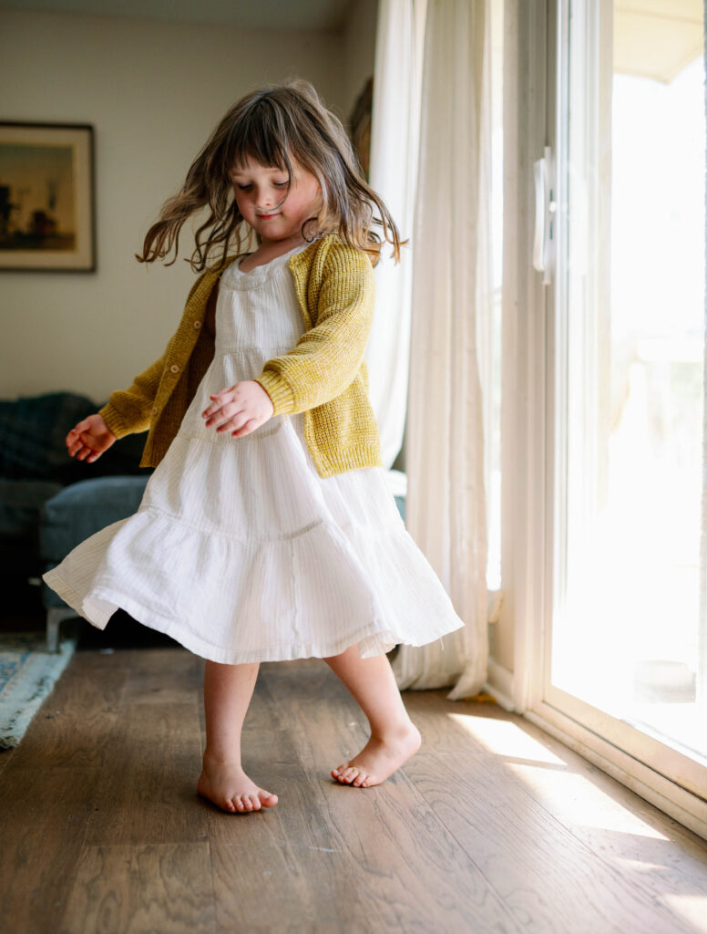 young girl twirling in the sunlit window