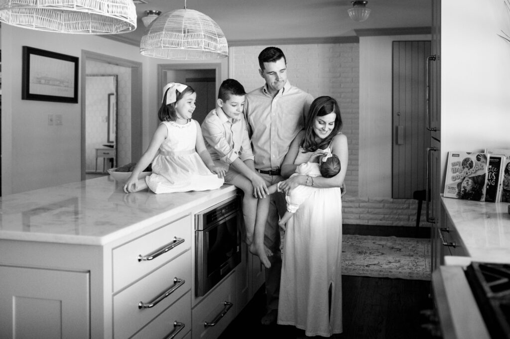 family in kitchen looking at newborn baby
