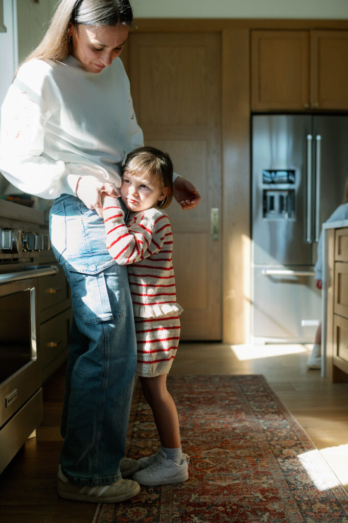 mom holding daughter standing in kitchen